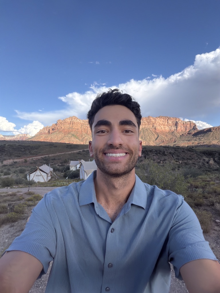 Avi smiling outdoors in front of red rock mountains